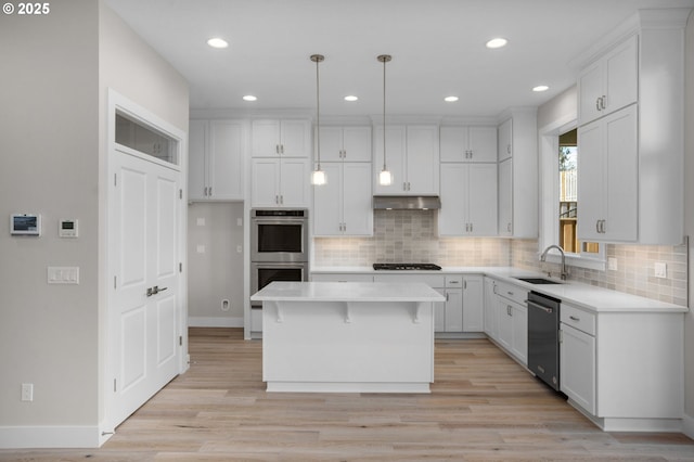 kitchen with appliances with stainless steel finishes, sink, a kitchen island, and white cabinets