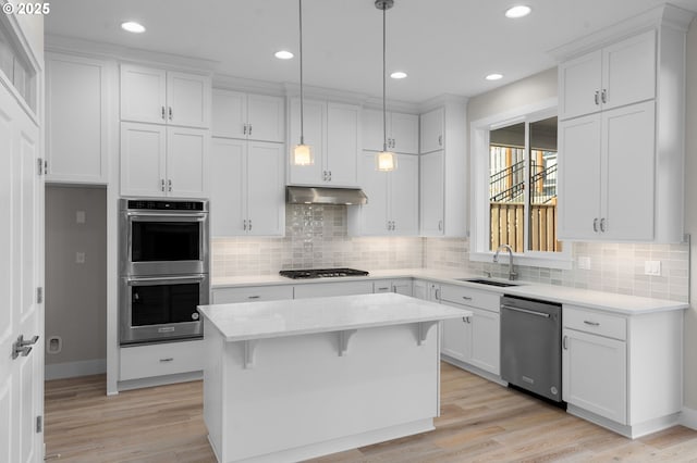 kitchen featuring decorative light fixtures, sink, white cabinets, a center island, and stainless steel appliances