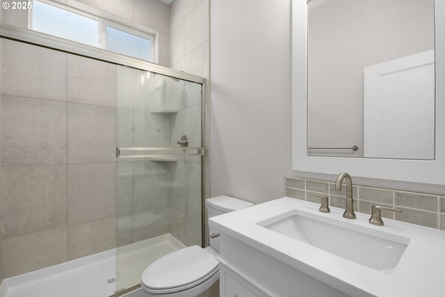 bathroom featuring vanity, decorative backsplash, a shower with door, and toilet