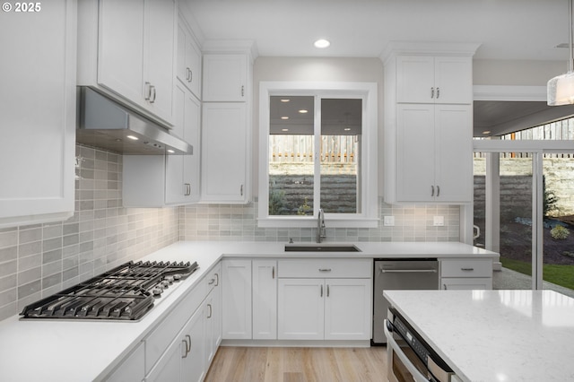 kitchen featuring sink, tasteful backsplash, light wood-type flooring, appliances with stainless steel finishes, and white cabinets