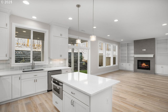 kitchen with pendant lighting, sink, white cabinets, and a kitchen island