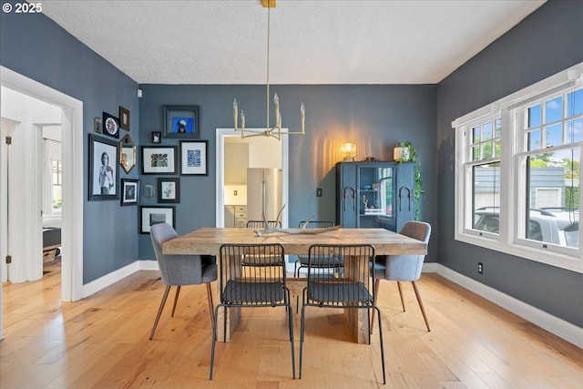 dining area with light wood-style floors, baseboards, and a textured ceiling