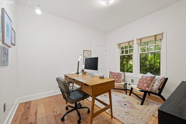office space with light wood-type flooring and baseboards