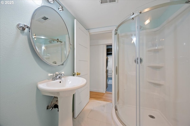 full bath featuring a shower stall, marble look tiles, and a sink