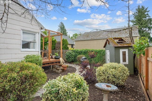 view of yard with a wooden deck, fence, a storage shed, and an outbuilding