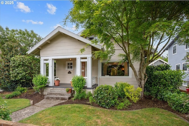 bungalow-style house featuring covered porch and a front yard