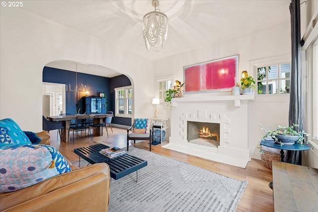 living room featuring arched walkways, a chandelier, healthy amount of natural light, and wood finished floors