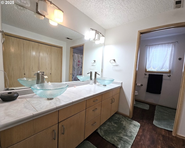 3300 NE 164th St Unit S-1, Ridgefield, WA 98642 - full bathroom with wood finished floors, toilet, a textured ceiling, double vanity, and baseboards
