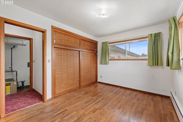 901 H Ave, La Grande, OR 97850 - unfurnished bedroom featuring a baseboard radiator, light wood finished floors, baseboards, and a closet