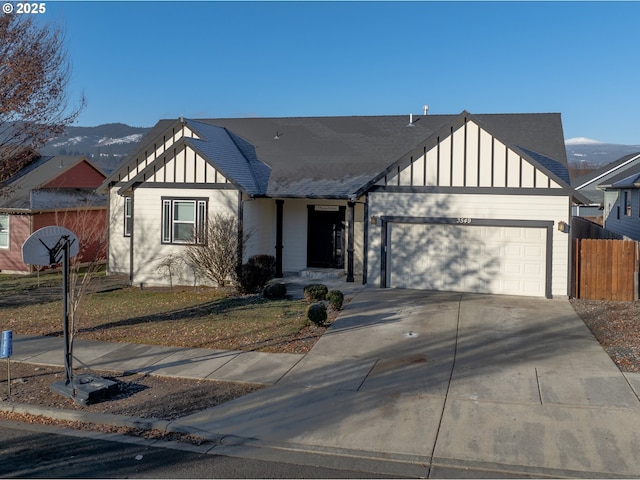 view of front of property with an attached garage, a shingled roof, fence, concrete driveway, and board and batten siding