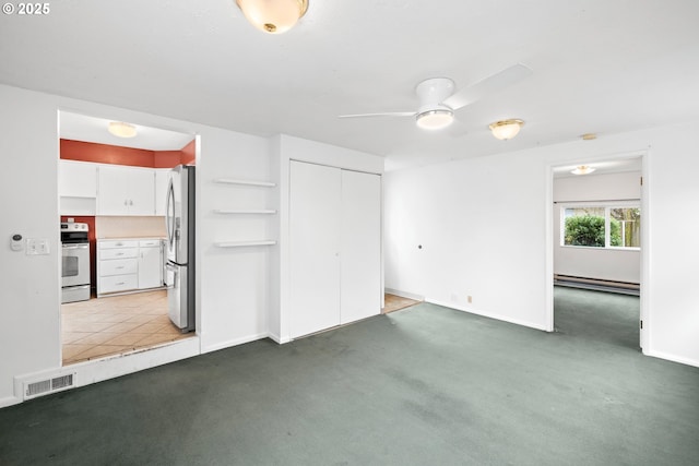 unfurnished bedroom with dark colored carpet, a baseboard heating unit, stainless steel fridge, and a closet