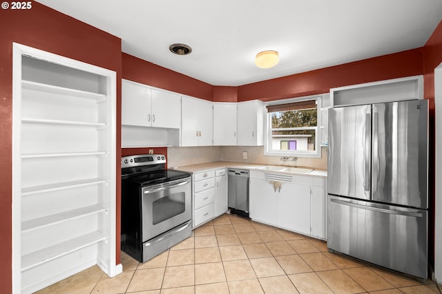 kitchen featuring sink, light tile patterned floors, appliances with stainless steel finishes, white cabinets, and decorative backsplash