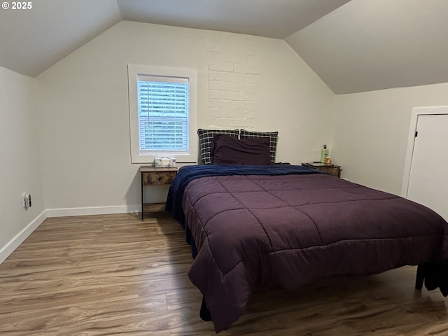 bedroom featuring light wood-style flooring, baseboards, and vaulted ceiling