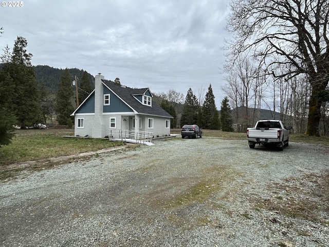 view of front of house featuring driveway, a chimney, and a front yard