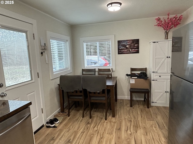 dining area with light wood-style floors, baseboards, and ornamental molding