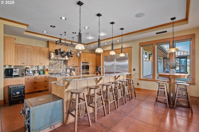 10771 E Langell Valley Rd, Bonanza, OR 97623 - kitchen featuring a tray ceiling, appliances with stainless steel finishes, light brown cabinets, tasteful backsplash, and a breakfast bar area