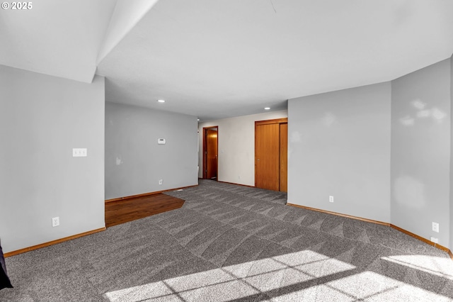 spare room with recessed lighting, dark carpet, and baseboards