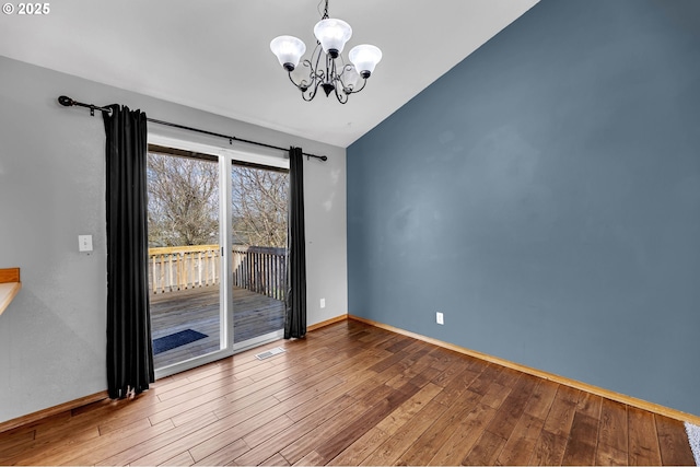 unfurnished room with a chandelier, wood finished floors, visible vents, baseboards, and vaulted ceiling