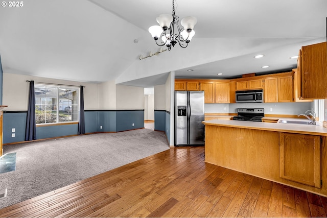 kitchen featuring light countertops, appliances with stainless steel finishes, open floor plan, a sink, and vaulted ceiling