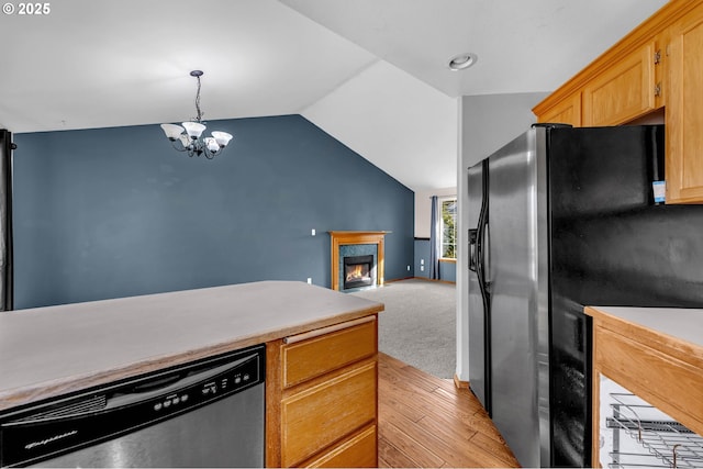 kitchen with lofted ceiling, light countertops, black fridge with ice dispenser, dishwasher, and a lit fireplace