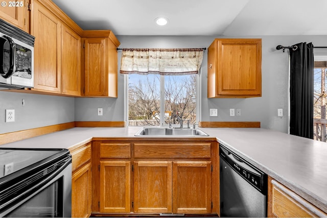 kitchen featuring brown cabinetry, appliances with stainless steel finishes, light countertops, a sink, and recessed lighting