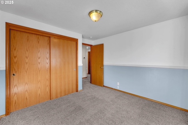 unfurnished bedroom with a closet, carpet, and baseboards