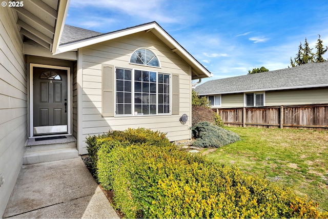 property entrance with fence and a lawn