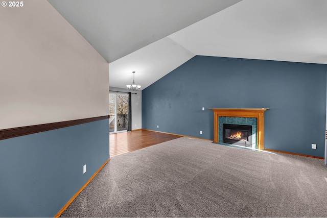 unfurnished living room with carpet floors, an inviting chandelier, a premium fireplace, and vaulted ceiling