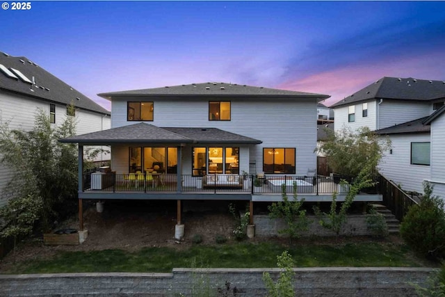 back of property at dusk featuring a wooden deck