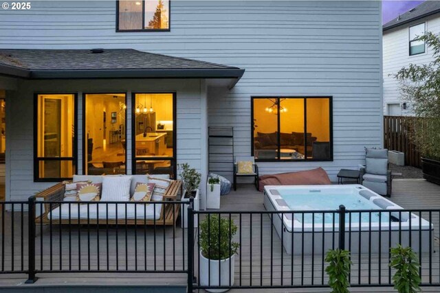 back of house with fence, an outdoor hot tub, a shingled roof, and an outdoor living space