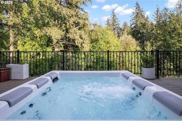 exterior space featuring a hot tub, a deck, and a view of trees