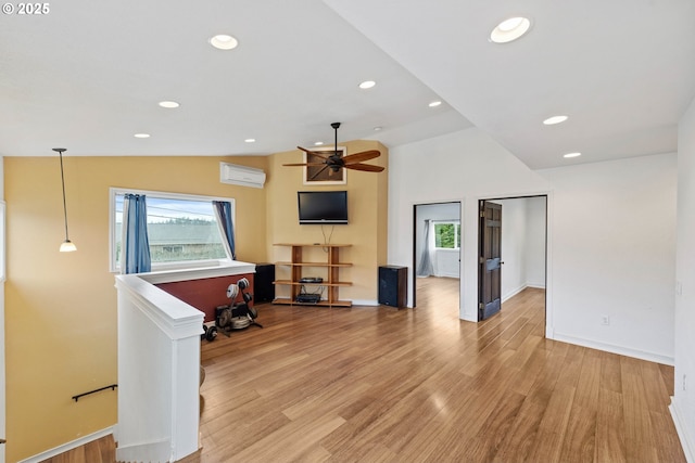 living room featuring light wood finished floors, plenty of natural light, vaulted ceiling, and a wall mounted air conditioner