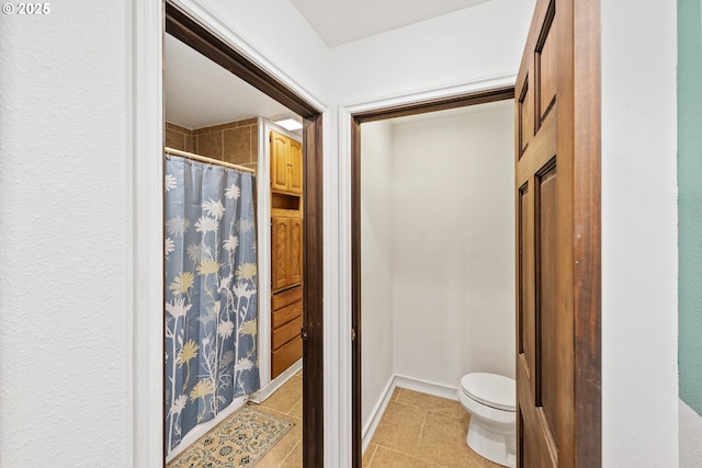 bathroom featuring tile patterned flooring, baseboards, curtained shower, and toilet