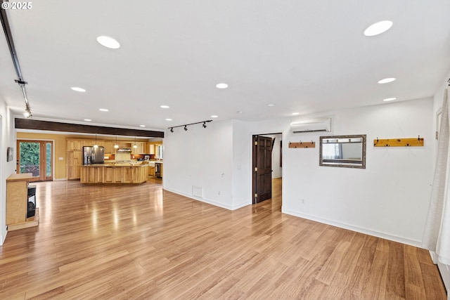 unfurnished living room featuring light wood finished floors, a wall mounted AC, and recessed lighting