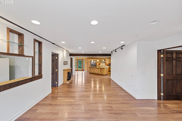 corridor with light wood-type flooring, baseboards, and recessed lighting