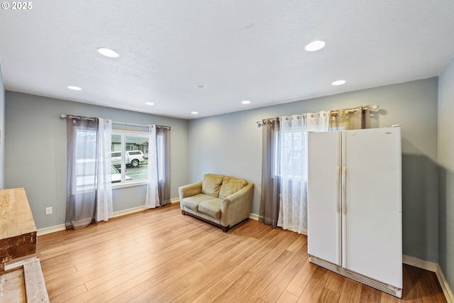 living area featuring light wood-type flooring, baseboards, a textured ceiling, and recessed lighting