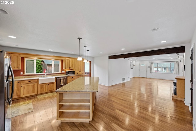 kitchen with a kitchen island, appliances with stainless steel finishes, open floor plan, hanging light fixtures, and a sink