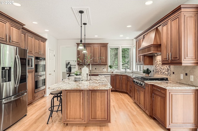 kitchen featuring appliances with stainless steel finishes, a sink, light stone counters, light wood-style floors, and custom range hood