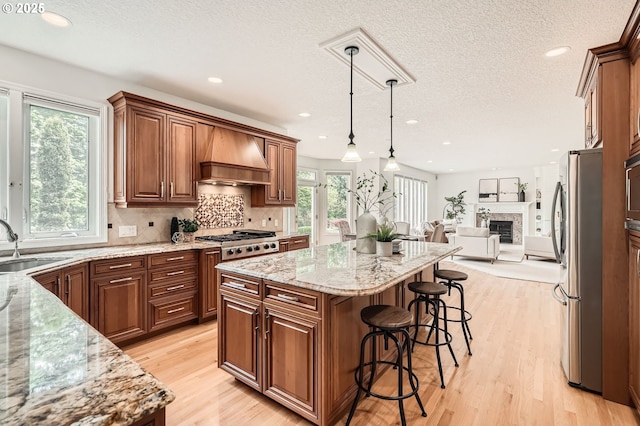 kitchen featuring a breakfast bar, a sink, premium range hood, a center island, and stainless steel appliances