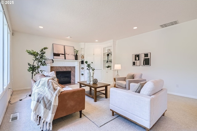 living room featuring recessed lighting, visible vents, a fireplace with flush hearth, and light carpet