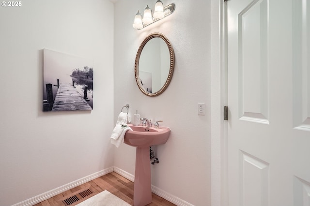 bathroom with baseboards, wood finished floors, and visible vents