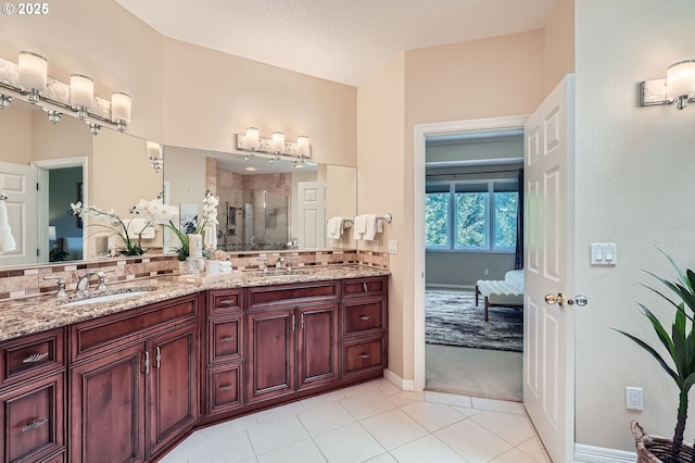 ensuite bathroom featuring a sink, tasteful backsplash, and a shower stall