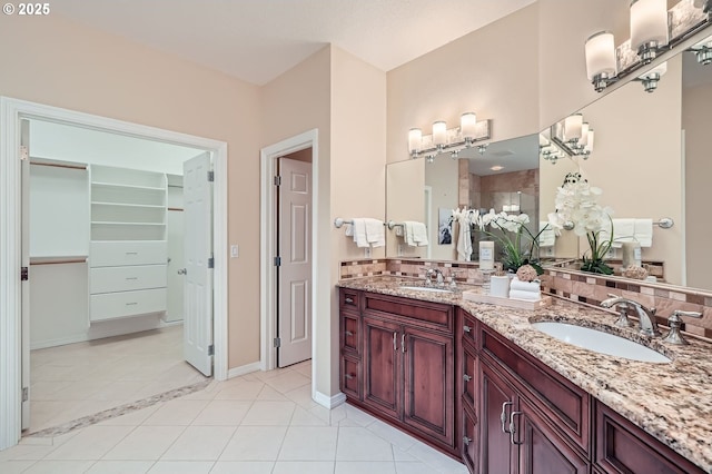 full bathroom featuring baseboards, double vanity, tile patterned floors, and a sink