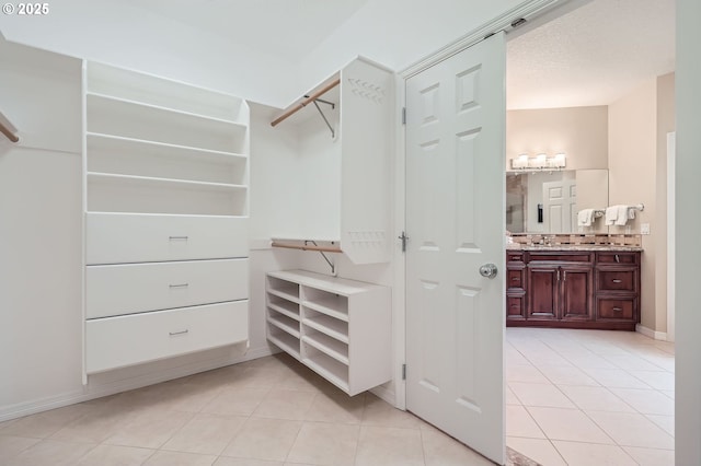 spacious closet featuring a sink and light tile patterned flooring