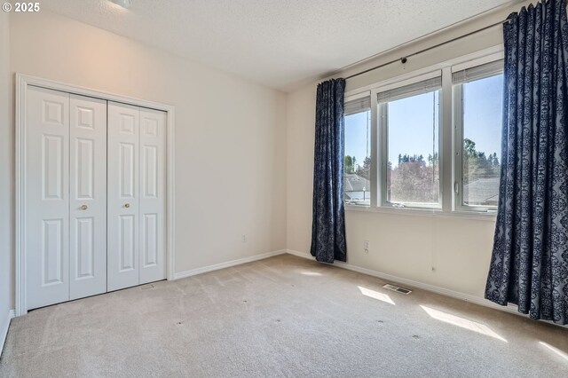 unfurnished bedroom with carpet floors, baseboards, a closet, and visible vents