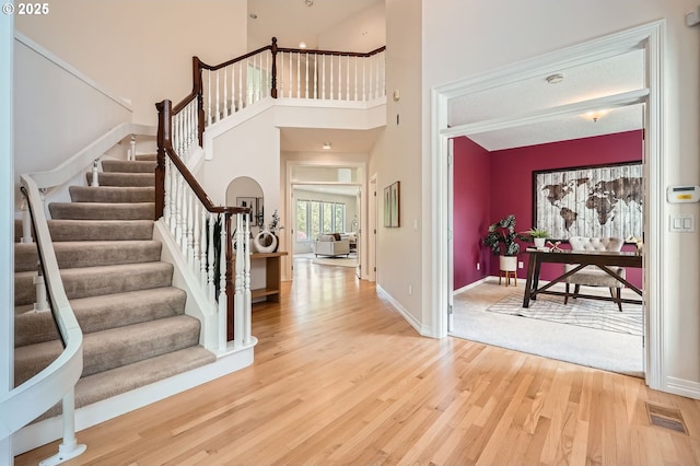 entrance foyer with baseboards, visible vents, wood finished floors, and stairway