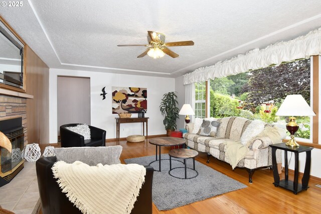 13275 NE Thompson Ct, Portland, OR 97230 - living room featuring a textured ceiling, ceiling fan, a fireplace, and wood finished floors