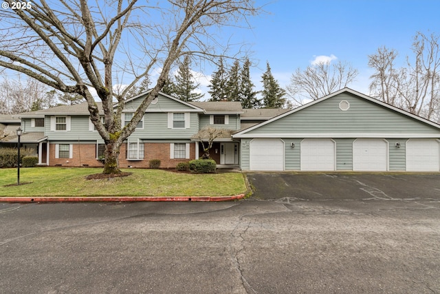 view of front of house featuring an attached garage, driveway, brick siding, and a front yard