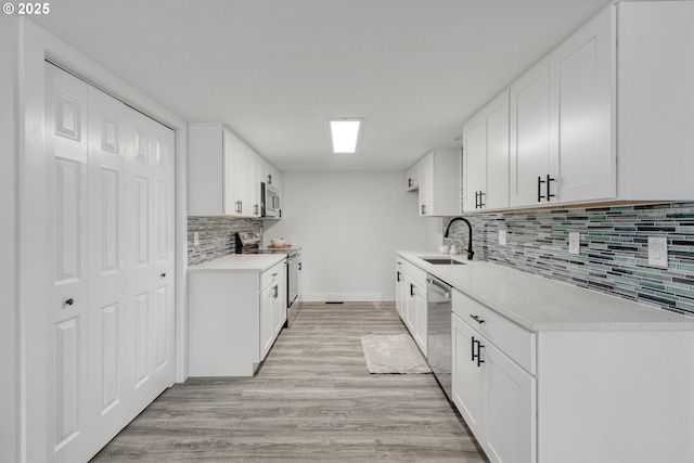 kitchen featuring appliances with stainless steel finishes, light countertops, light wood-style floors, white cabinetry, and a sink