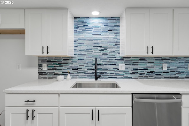 kitchen with decorative backsplash, white cabinetry, a sink, and stainless steel dishwasher